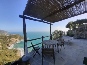 Eine Terrasse mit Blick auf das Meer und die Hügel, komplett mit Tisch und Stühlen.