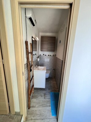 Ein kleines Badezimmer mit einem weißen Waschbecken, einer Toilette und einem Spiegel über dem Waschbecken.