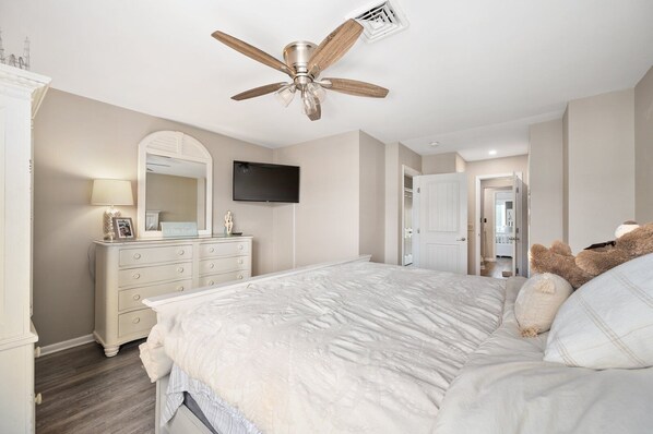 A bedroom with a bed, a dresser, a vanity, a ceiling fan, and a TV mounted on the wall. - Nassau Village 7 - 2 level townhome on canal with outdoor pool, 2 br 1.5 baths (Ocean City)