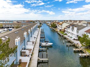 A canal lined with row houses, docks, and a boat. - Nassau Village 7 - 2 level townhome on canal with outdoor pool, 2 br 1.5 baths (Ocean City)