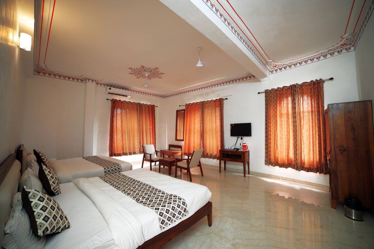 A hotel room with a large bed, a desk, a chair, and a television.