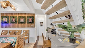 A modern dining area with a wooden table and chairs, a wall-mounted plant display, and a dartboard.
