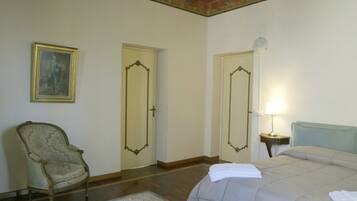 Habitación de hotel con una cama, una silla, dos puertas, una lámpara y un cuadro en la pared.