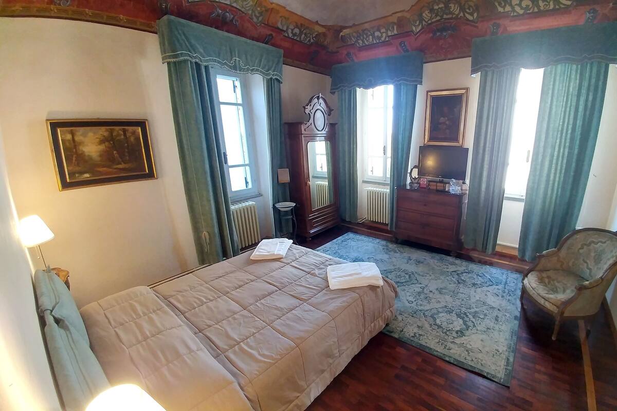 A bedroom with a bed, a chair, a dresser, and a radiator.
