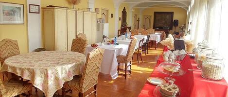 Un comedor con varias mesas, sillas y una mesa de buffet.