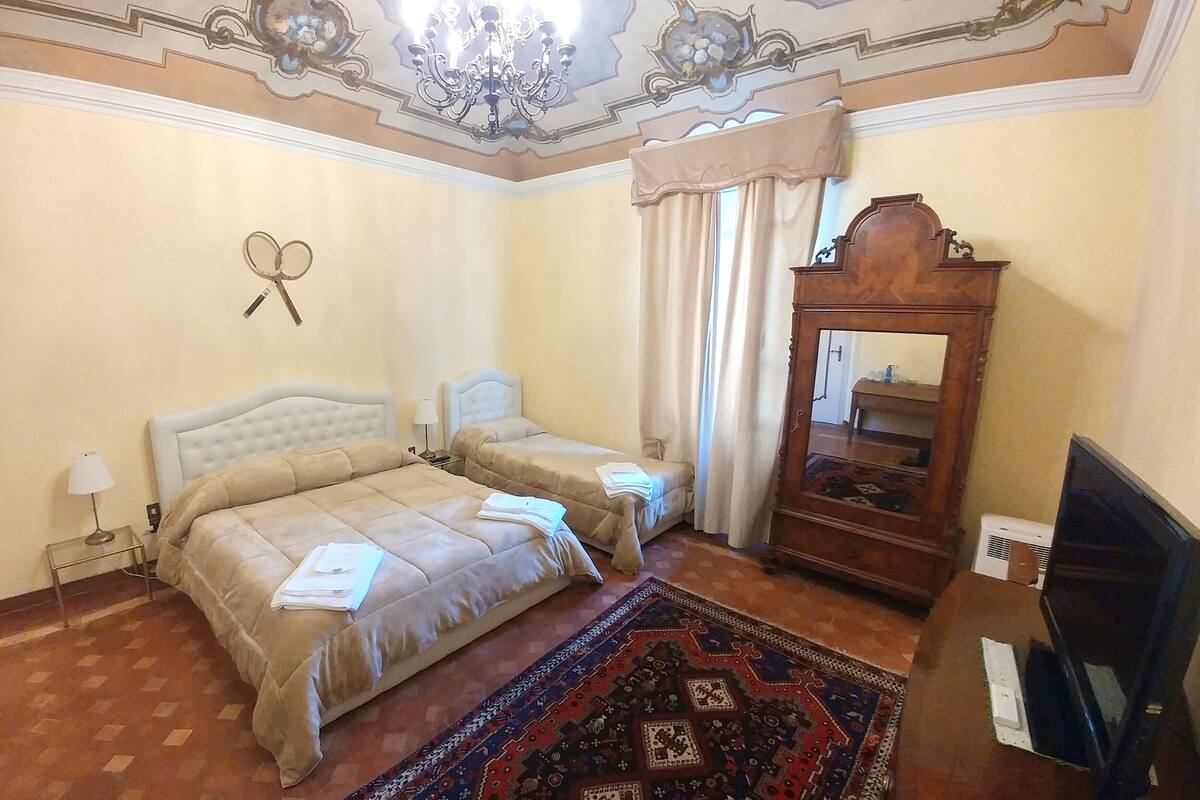 A hotel room with two beds, a large mirror, a television, and a patterned rug.