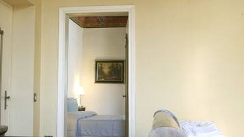 Una habitación con una cama de madera, un banco, una puerta y un cuadro en la pared.