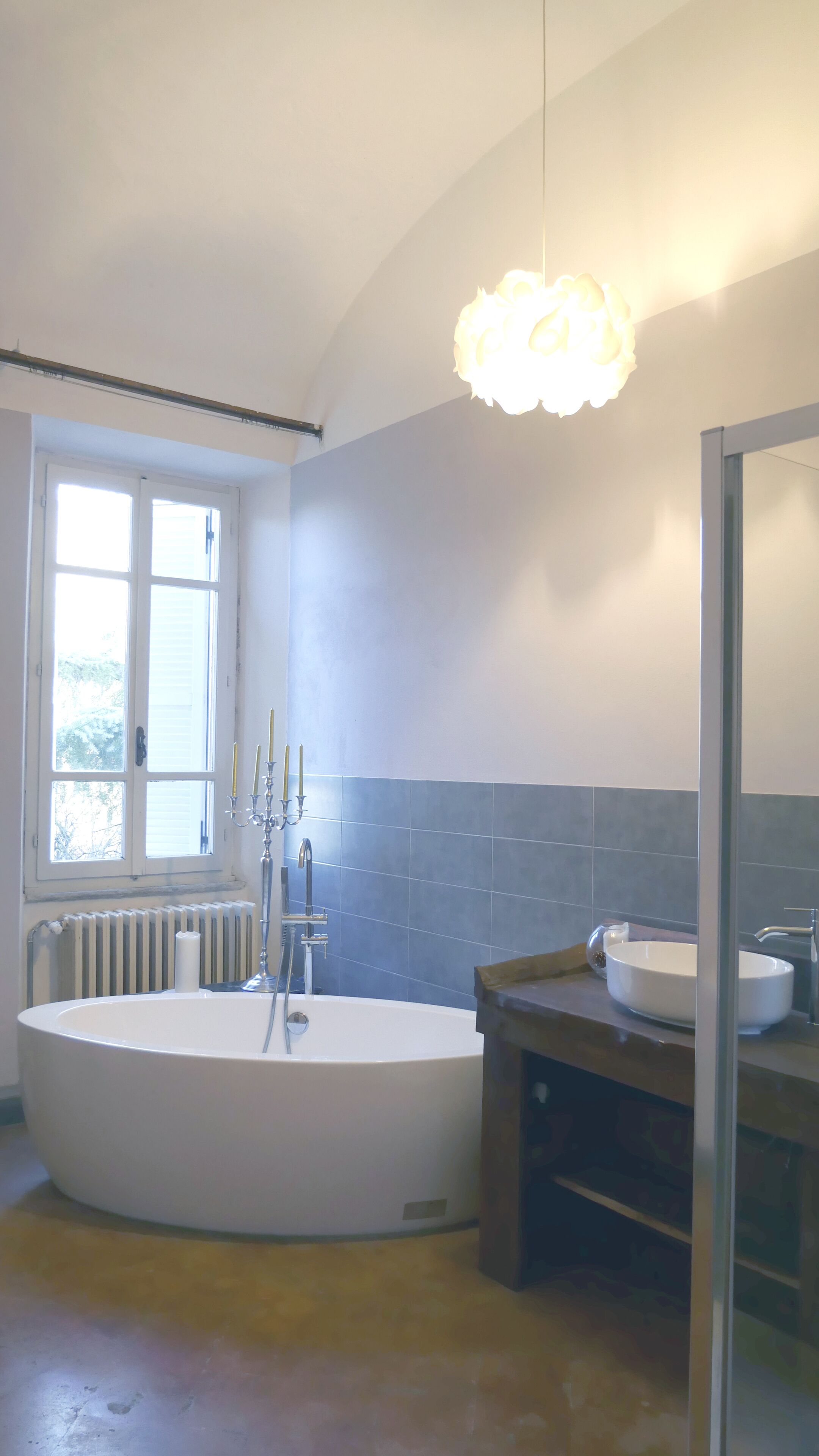Een badkamer met een groot bad, een raam en een spiegel.