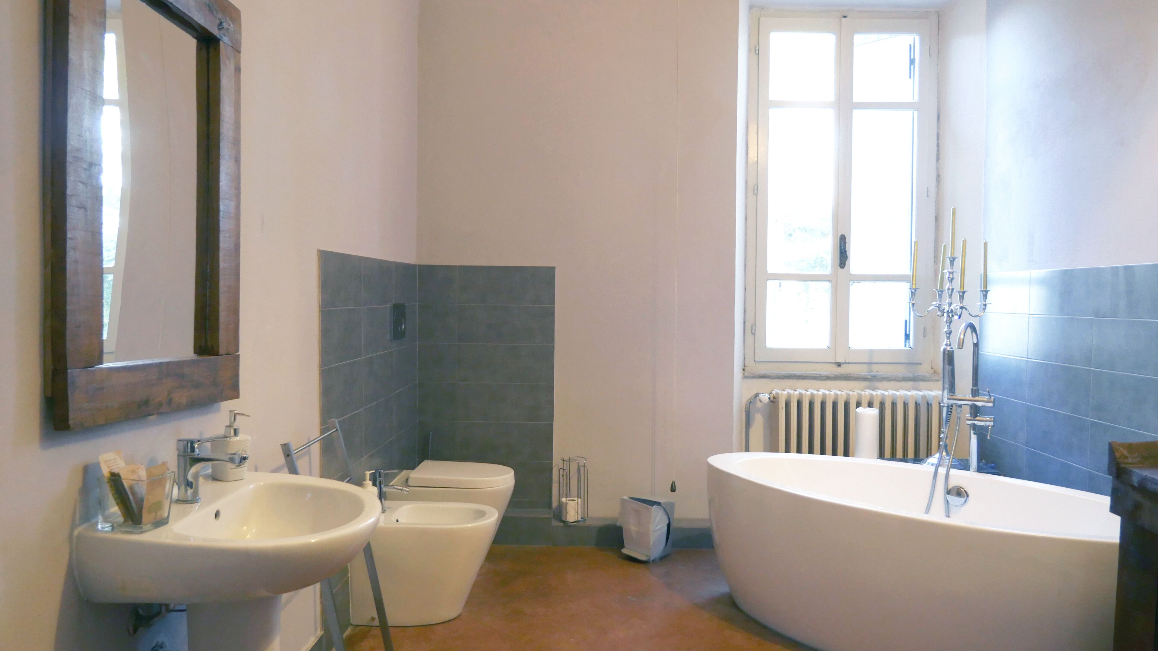 Un bagno con lavandino, due servizi igienici, una vasca e una finestra.
