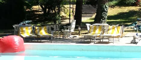 Una piscina al aire libre de temporada, tumbonas