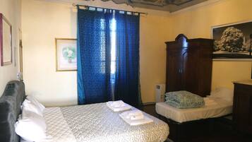 A room with a bed, a smaller bed, a wardrobe, and a framed picture on the wall.