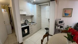 A compact kitchen with a stove, sink, and refrigerator. There is a dining area with a table and chairs, and a small TV on a stand. - Charme Holidays Venice (Venice)