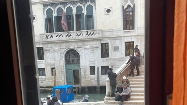 A courtyard with stone paving, a blue covered object, and a building with arched windows and a green door. - Charme Holidays Venice (Venice)