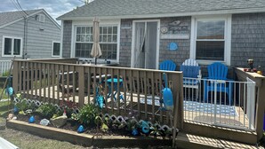 Una propiedad residencial con un porche cubierto, mobiliario exterior y una pared decorativa con peces.