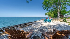 A wooden deck with chairs and a table overlooking a calm sea. - Wait 'n Sea Lake house near Point Pelee (Leamington)
