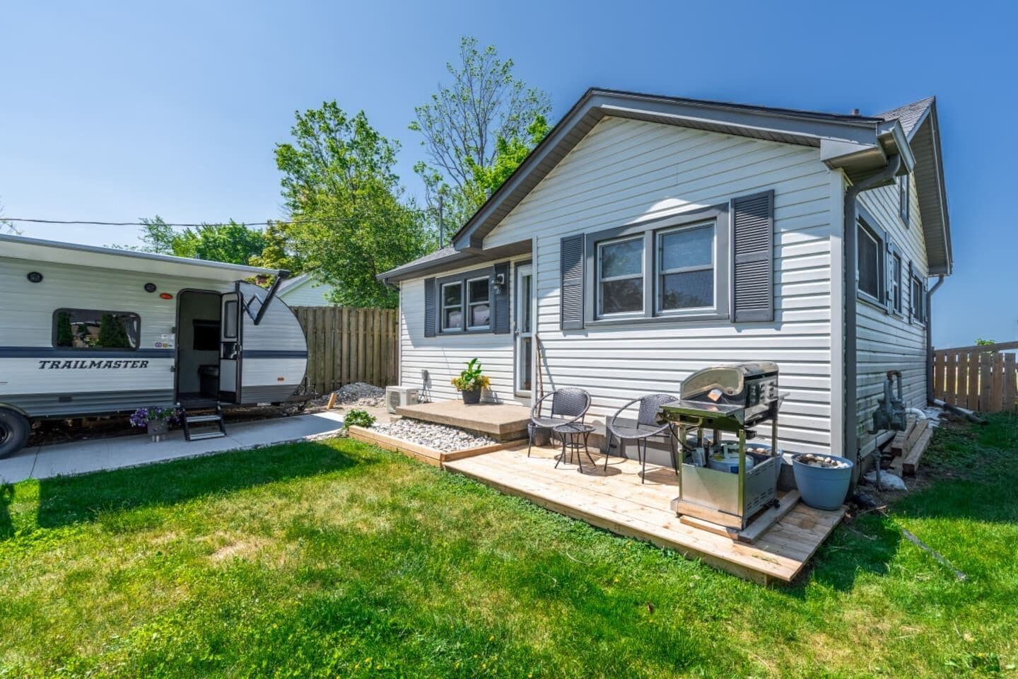 A mobile home with a patio area, outdoor seating, and a grill.
