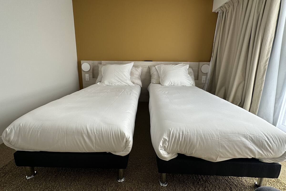 Una cama doble con cabecera, una mesita de noche y una cortina.