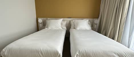 Un lit double avec une tête de lit, deux oreillers et une table de chevet avec une lampe.