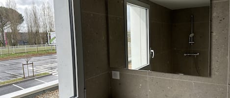 A modern bathroom with a large window, a sink, and a shower.