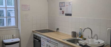 A kitchen with white cabinets, a wooden countertop, a sink, and a window.
