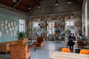 Una biblioteca amplia con varias zonas de descanso, estanterías y obras enmarcadas en las paredes.