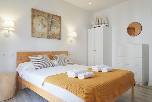 Quarto de hotel bem arrumado, com uma cama, um guarda-roupa, um mapa na parede e uma réplica de navio.