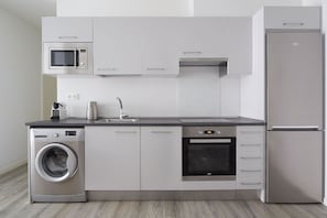 Uma cozinha moderna equipada com micro-ondas, forno, máquina de lavar louça e frigorífico.