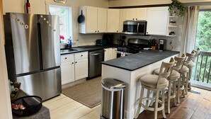 A modern kitchen with stainless steel appliances, a central island with bar stools, and a view of the outdoors.