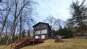 A two-story wooden cabin with a wooden staircase leading up to a deck.