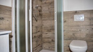 Un bagno con cabina doccia, un water e un pannello comandi a parete.