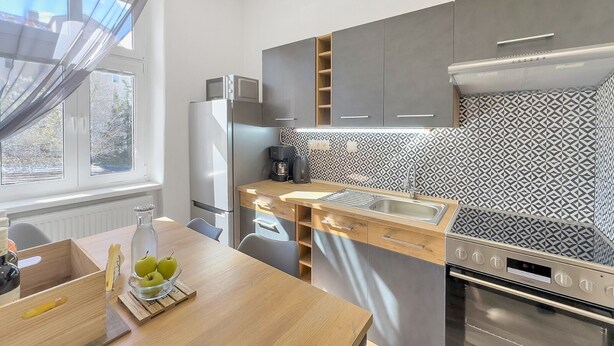Una cocina moderna con horno empotrado, cafetera y un salpicadero decorativo.