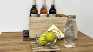 Una caja de madera con botellas de vino y un tarro de vidrio sobre una mesa de madera.