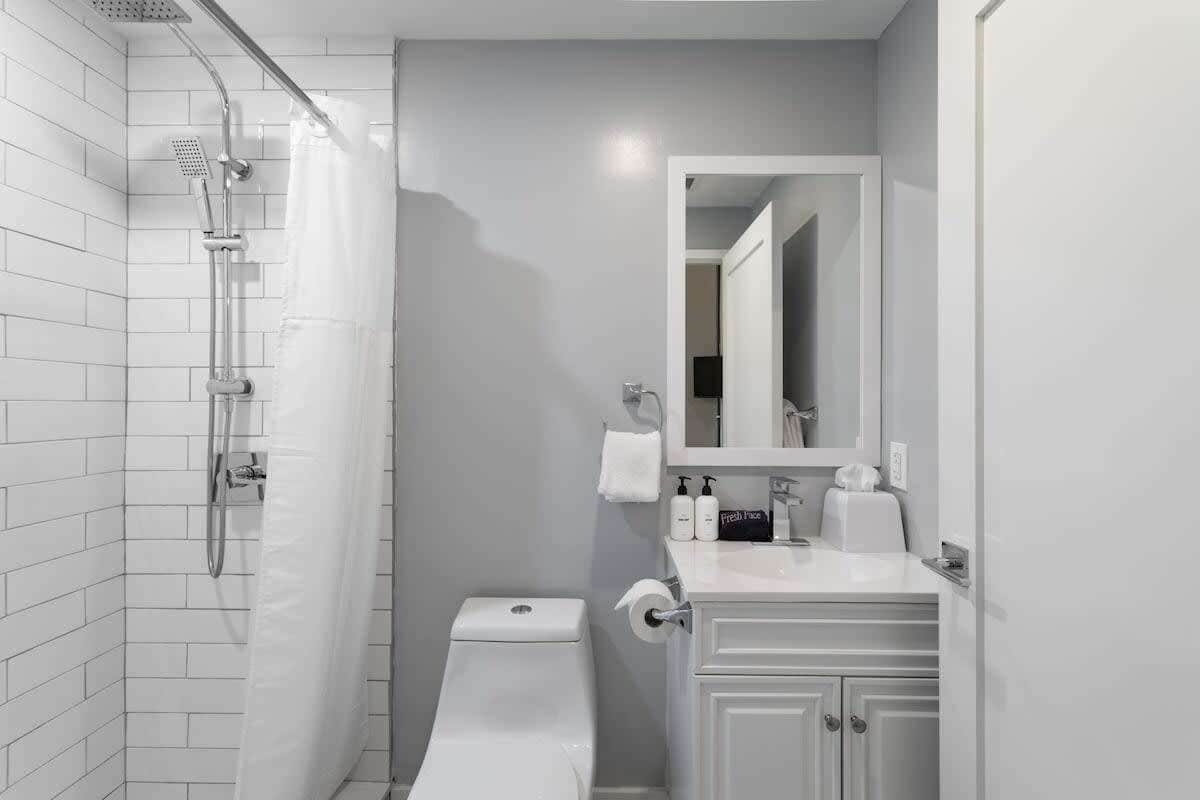 Une salle de bain moderne équipée d’une douche, de toilettes et d’un meuble-lavabo avec un miroir.