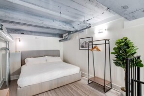 Une chambre à coucher moderne avec un lit, un radiateur, une plante et un porte-manteau.