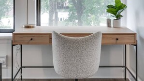 Un espace de travail moderne comprenant un bureau, une chaise et de grandes fenêtres donnant sur un espace vert.