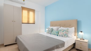 Een slaapkamer met een bed, nachtkastjes, een kledingkast en een raam met zonwering.