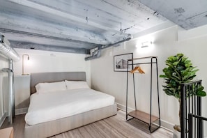 Une chambre à coucher moderne avec un lit, un radiateur, une plante et un porte-manteau.