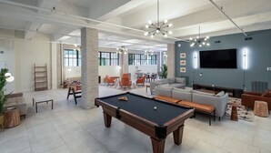 A spacious indoor area with a pool table, sofas, and a large flat-screen TV. - Sosuite | 2BR Loft w W/D, Gym, Lounge (Philadelphia)