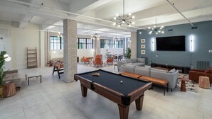 A modern living room with a pool table, sofas, and a TV. - Sosuite | 1BR Loft w W/D, Gym, Lounge (Philadelphia)