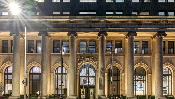 A large, historic building with a grand entrance, multiple columns, and large arched windows. - Sosuite | 1BR Loft w W/D, Gym, Lounge (Philadelphia)