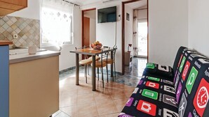 Un espace de vie compact comprenant un coin cuisine, un coin repas et un canapé aux motifs colorés.