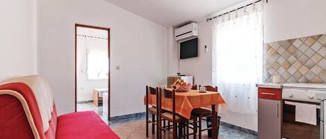 Un espacio habitable compacto con comedor, kitchenette y un sofá rojo.