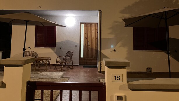 Un edificio con un balcone, una porta in legno e un cartello con il numero 18.