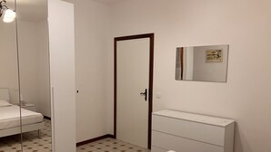 Una camera da letto con un letto, una cassettiera, uno specchio e una porta.