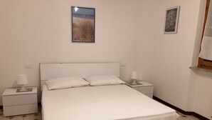 Una camera da letto con un letto, due comodini, due lampade a parete e due quadri appesi.