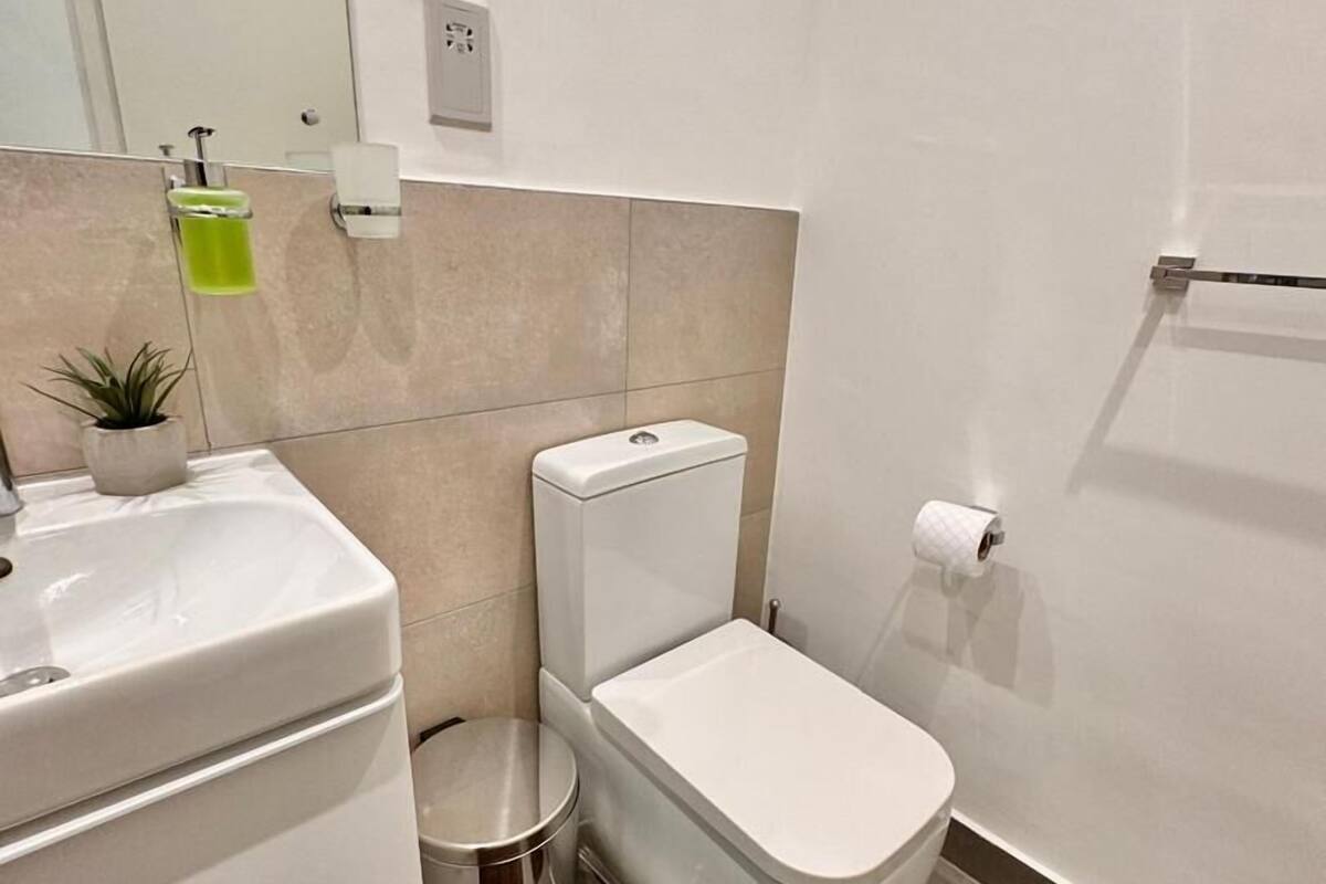 A modern bathroom with a toilet, sink, and mirror.