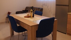 Ein Essbereich mit einem Holztisch, blauen Stühlen, einer Weinflasche und einem Glas.
