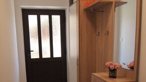Ein Flur mit einem Holzschrank, einem Spiegel und einer Tür mit satinierten Glasscheiben.