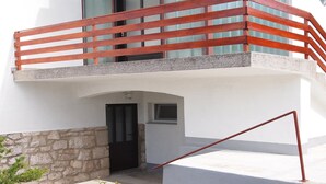 Ein modernes Gebäude mit einem Balkon, der einen roten Geländer, eine Steinsockel und eine kleine Eingangstür besitzt.