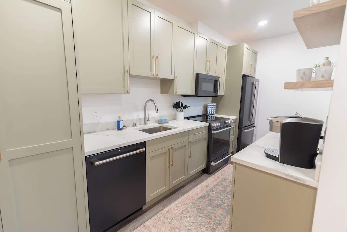 A compact kitchen with light-colored cabinets, a microwave, a refrigerator, and a coffee maker.